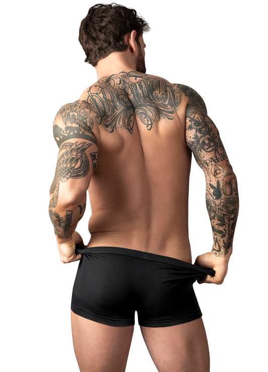 Man with tattoos on his back and arms holding up black underwear against a white background