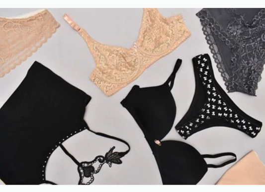 One Nude Bra, Two Black Bras, and Three Panties on A Dull, White Surface